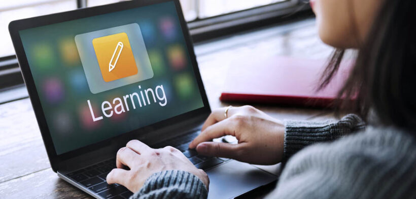 Person using a laptop with a screen displaying an app icon and the word "Learning," indicating an online or digital learning platform.